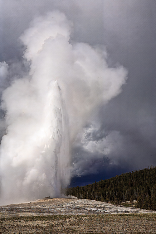 Dark sky behind Old Faithful in eruption